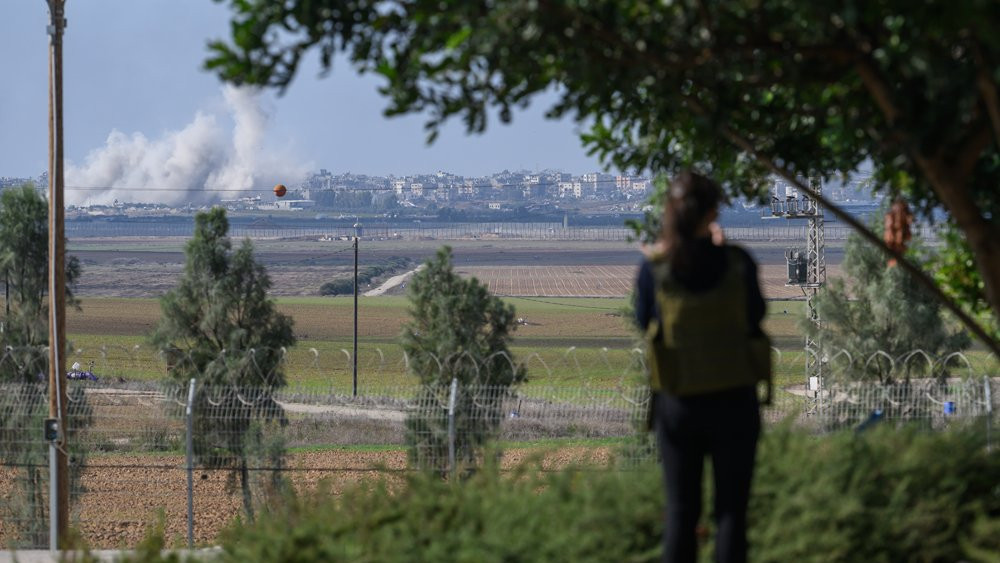 The great aunt of a recently-released hostage stands in a garden while looking out to Gaza in the distance with smoke rising from Israeli shelling, in southern Israel on 6 December.