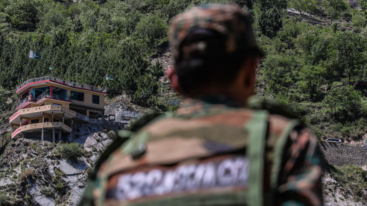 Pakistanska zastava i zgrade dok ih gleda vojnik u selu Simari na indijskoj strani Linije kontrole
